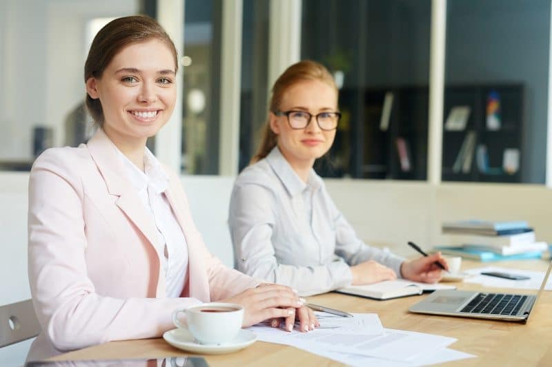 Two women smiling while working on bookkeeping for small business